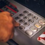 A hand pressing a button on an ATM keypad in Brasil, emphasizing digital banking.